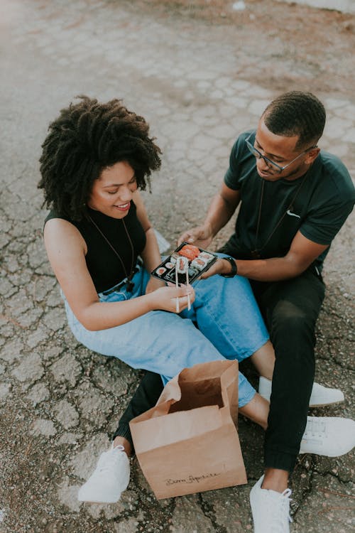 A man and woman sitting on the ground with a box