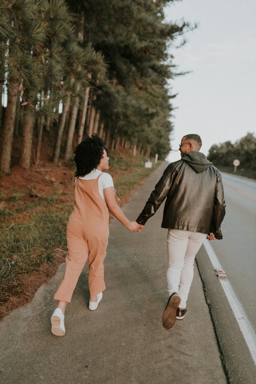 A couple holding hands walking down a road