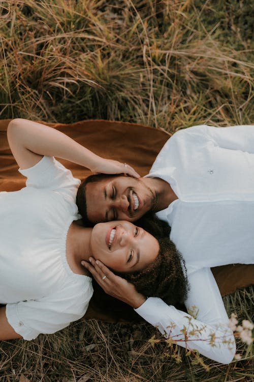 Free Smiling Woman and Man Lying Down on Grass and Hugging Stock Photo