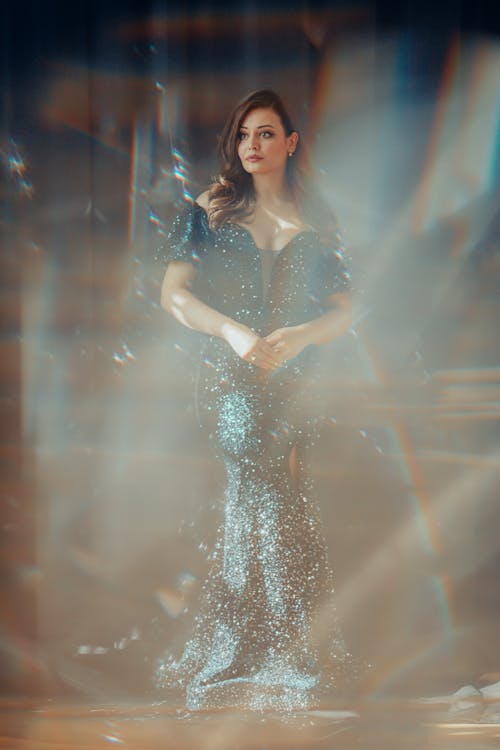 A woman in a blue dress is standing in front of a light