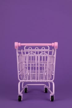 Minimalist image of a pastel pink shopping cart against a vibrant purple background, ideal for abstract concepts.