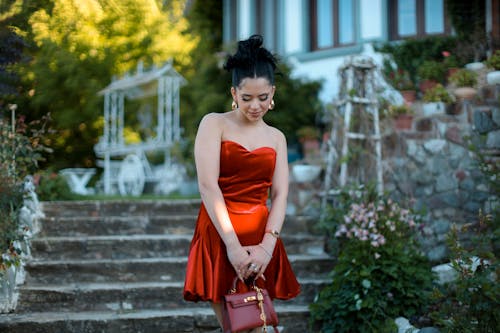 A woman in a red dress and heels is posing for a picture