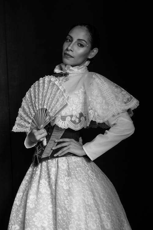A woman in a dress holding a fan
