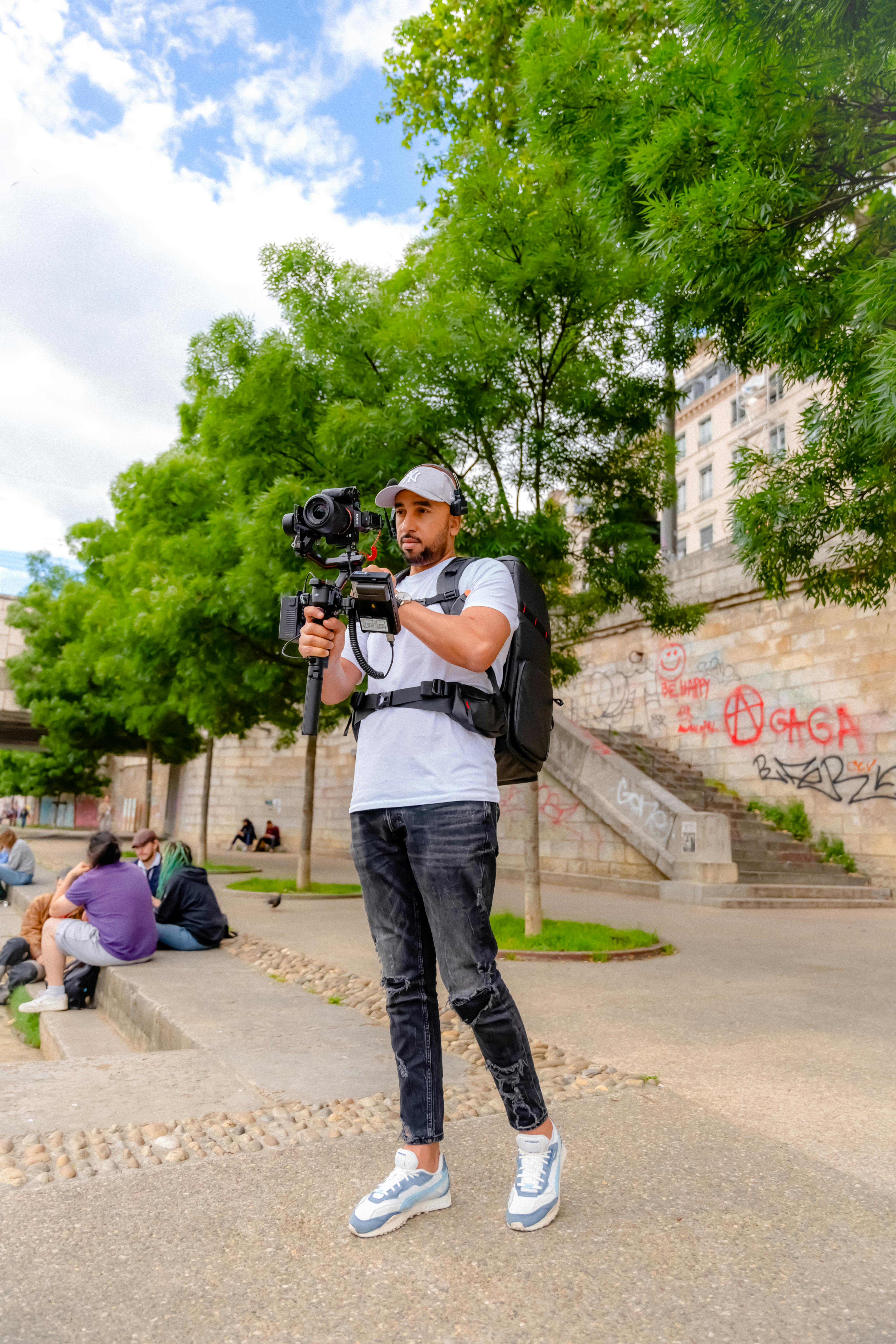 man recording video with camera on tripod in park