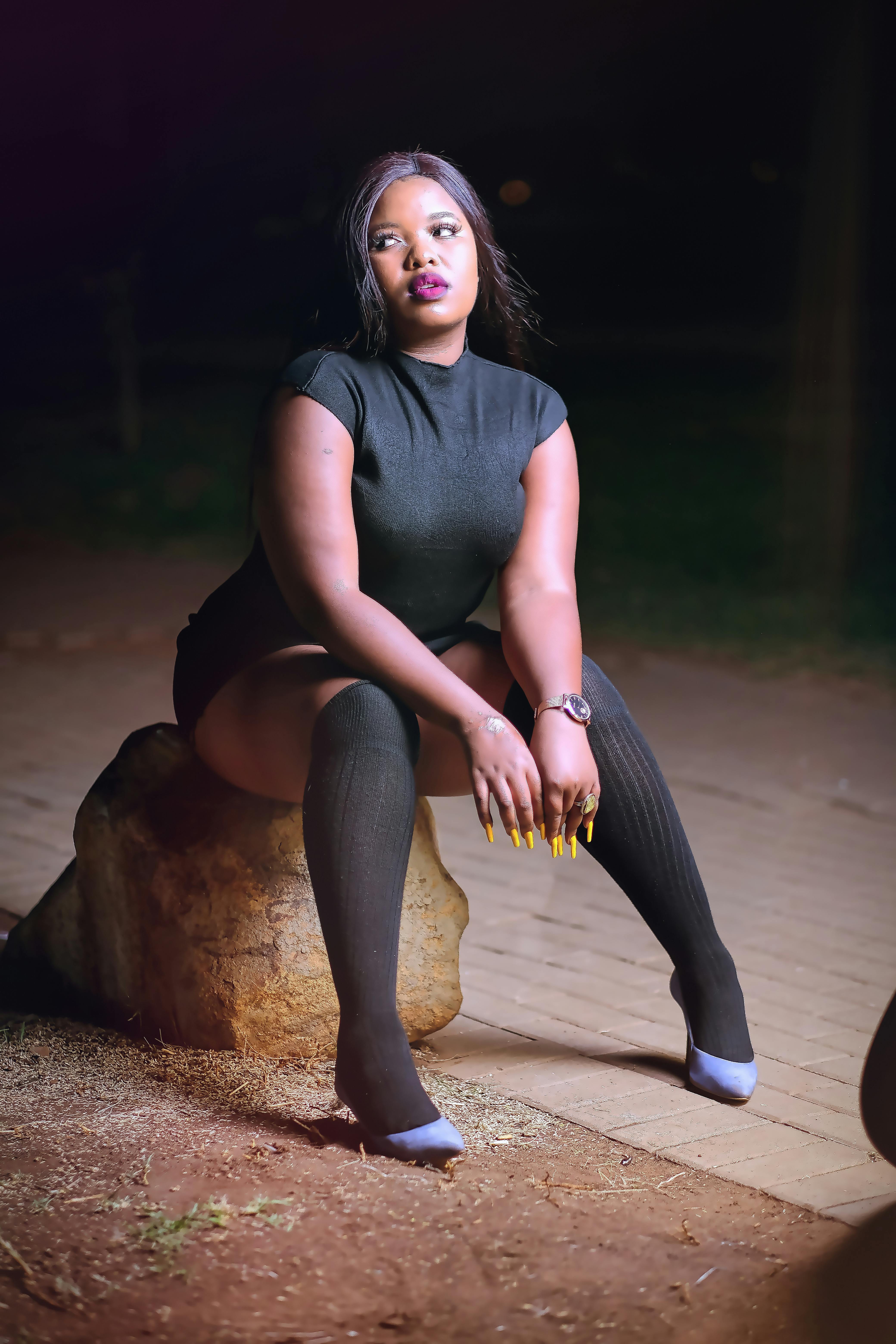 晚上，穿着黑色服装的时装模特在岩石上优雅地摆姿势