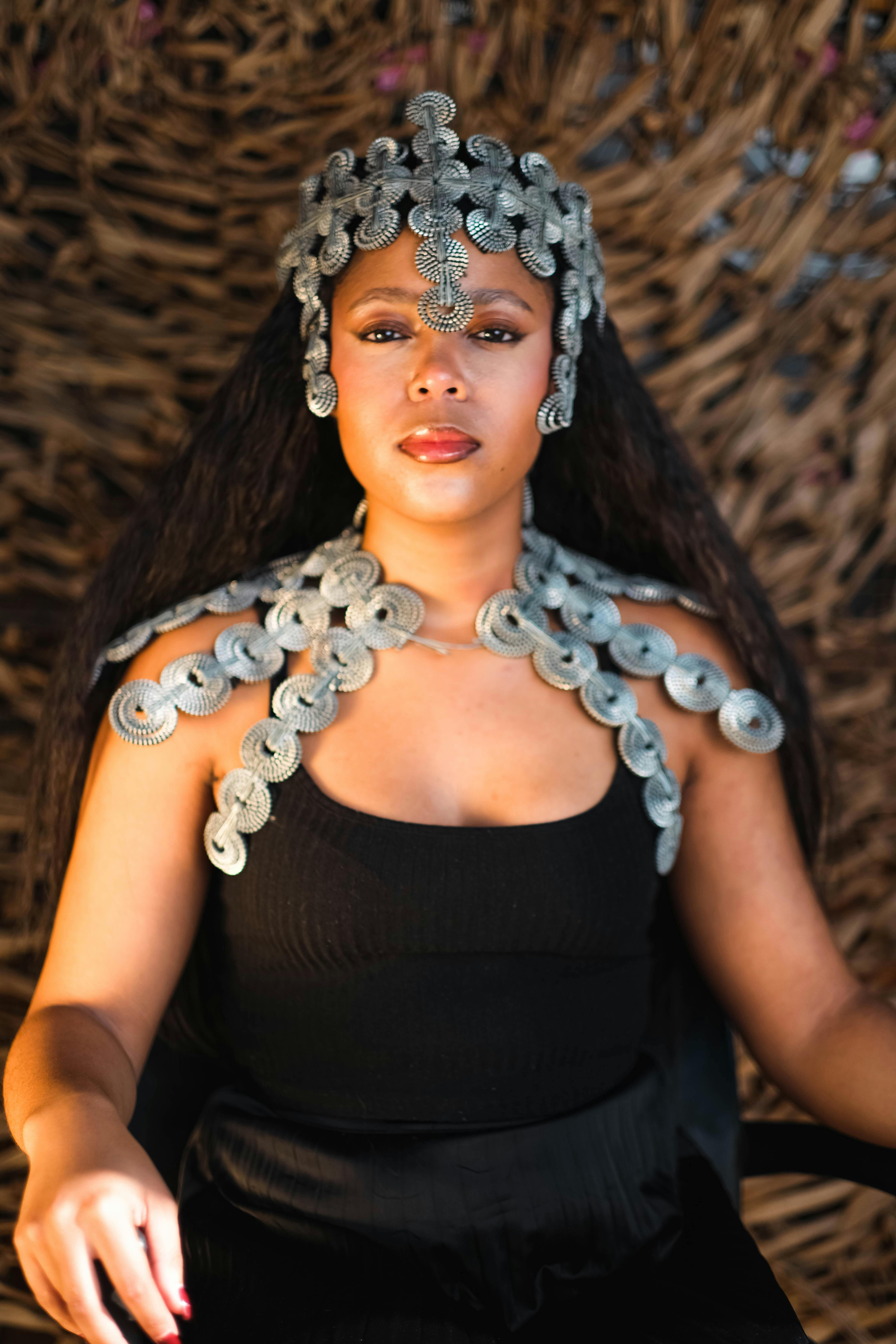A striking portrait of a woman in black dress adorned with exquisite metal jewelry, radiating elegance and poise.