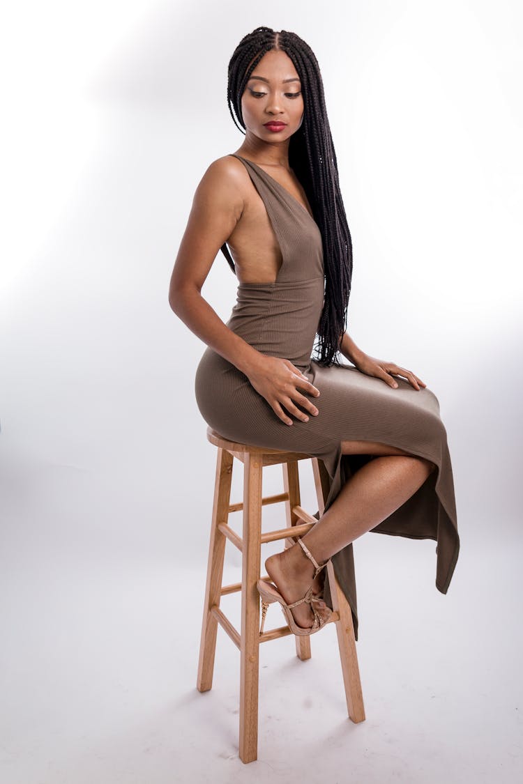 Photo Of Woman Wearing Brown Dress While Sitting On Stool