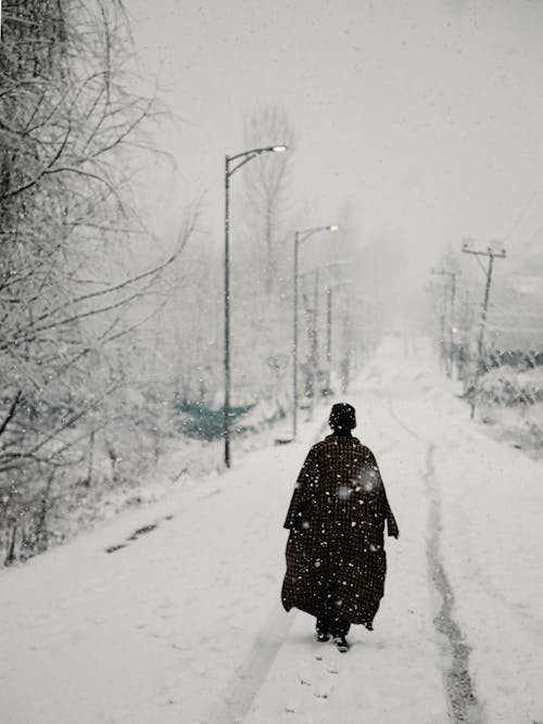 A man walks down a snowy street in kabul