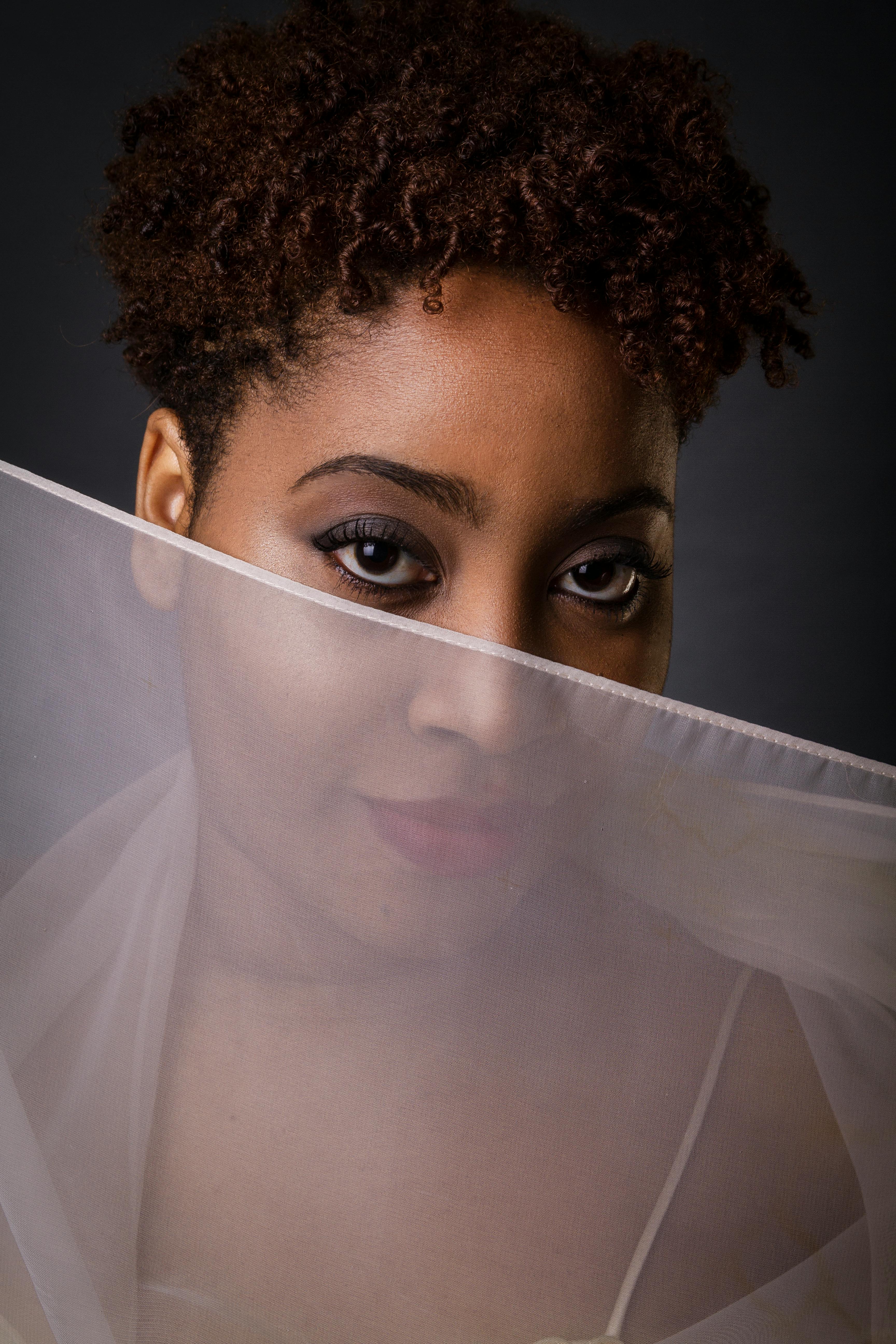 closeup photo of a woman covering her face with a white sheer