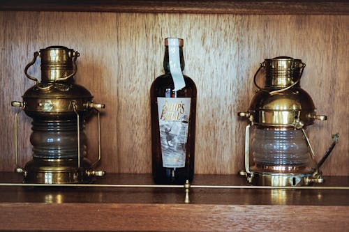 A shelf with two bottles and two lanterns