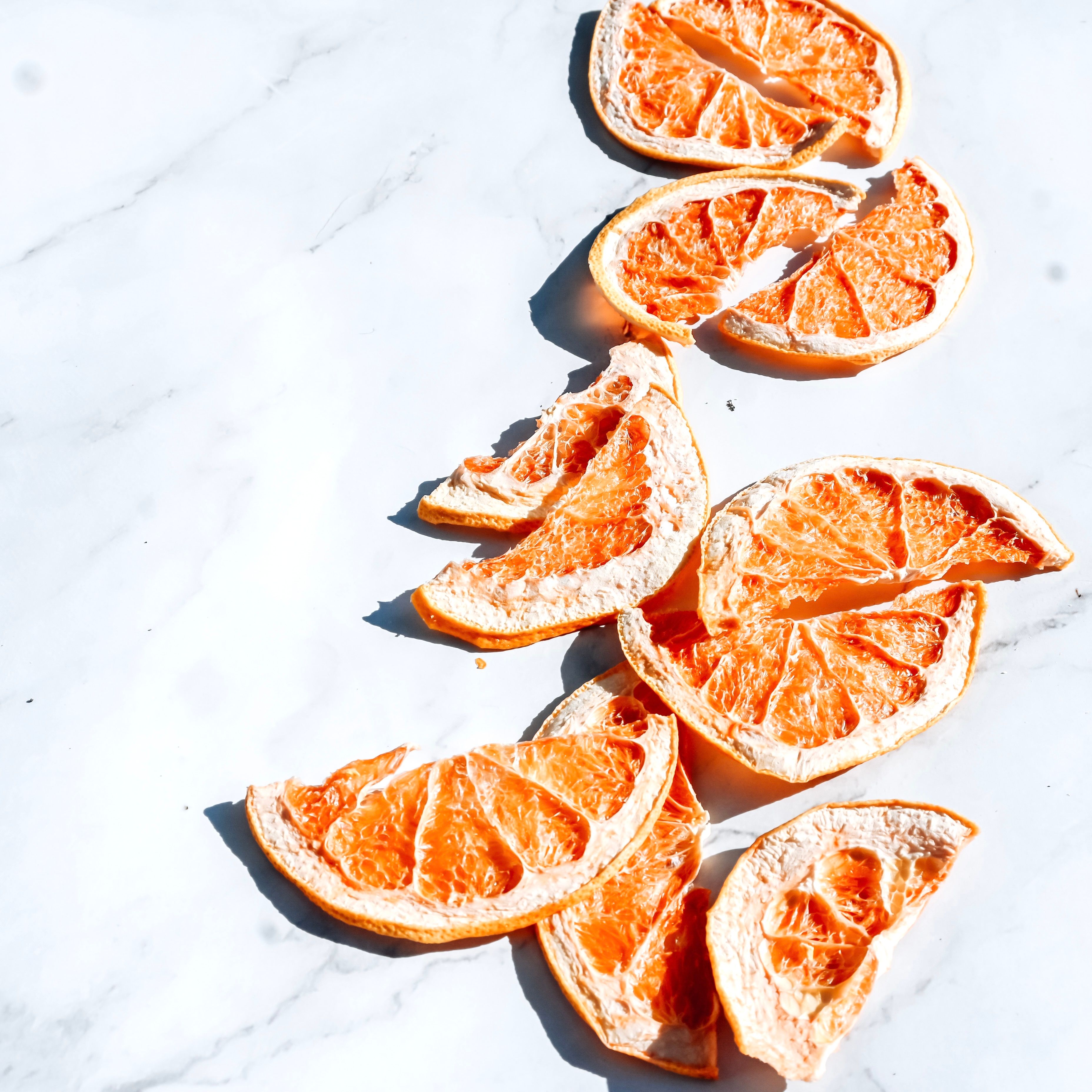Artistic arrangement of dried orange slices on a white marble background.