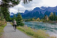 秋天，骑自行车的人沿着风景如画的河道骑行，背景是迷人的山间景色