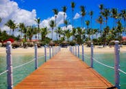 木制码头通向一个热带海滩度假村，那里有棕榈树和清澈蔚蓝的海水