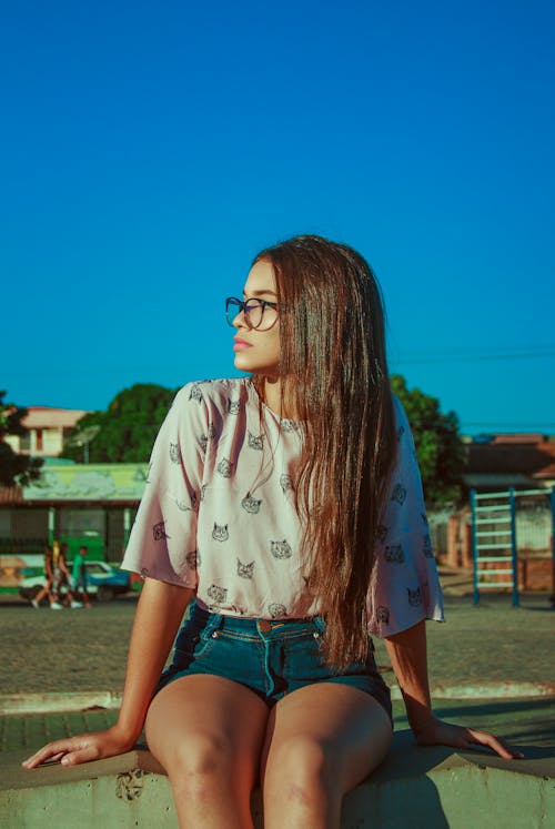 Photo of a Woman Wearing a pink top and shorts sitting down looking away