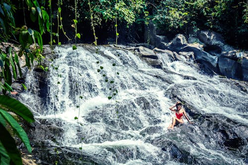 Free Photo of Woman Sitting on Rocks Near Waterfalls Stock Photo