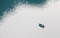 两名渔民在宁静的水域划艇，四周环绕着温柔的涟漪和倒影