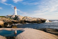 岩石海岸上的灯塔、海浪与明亮的天空，构成完美的海事主题