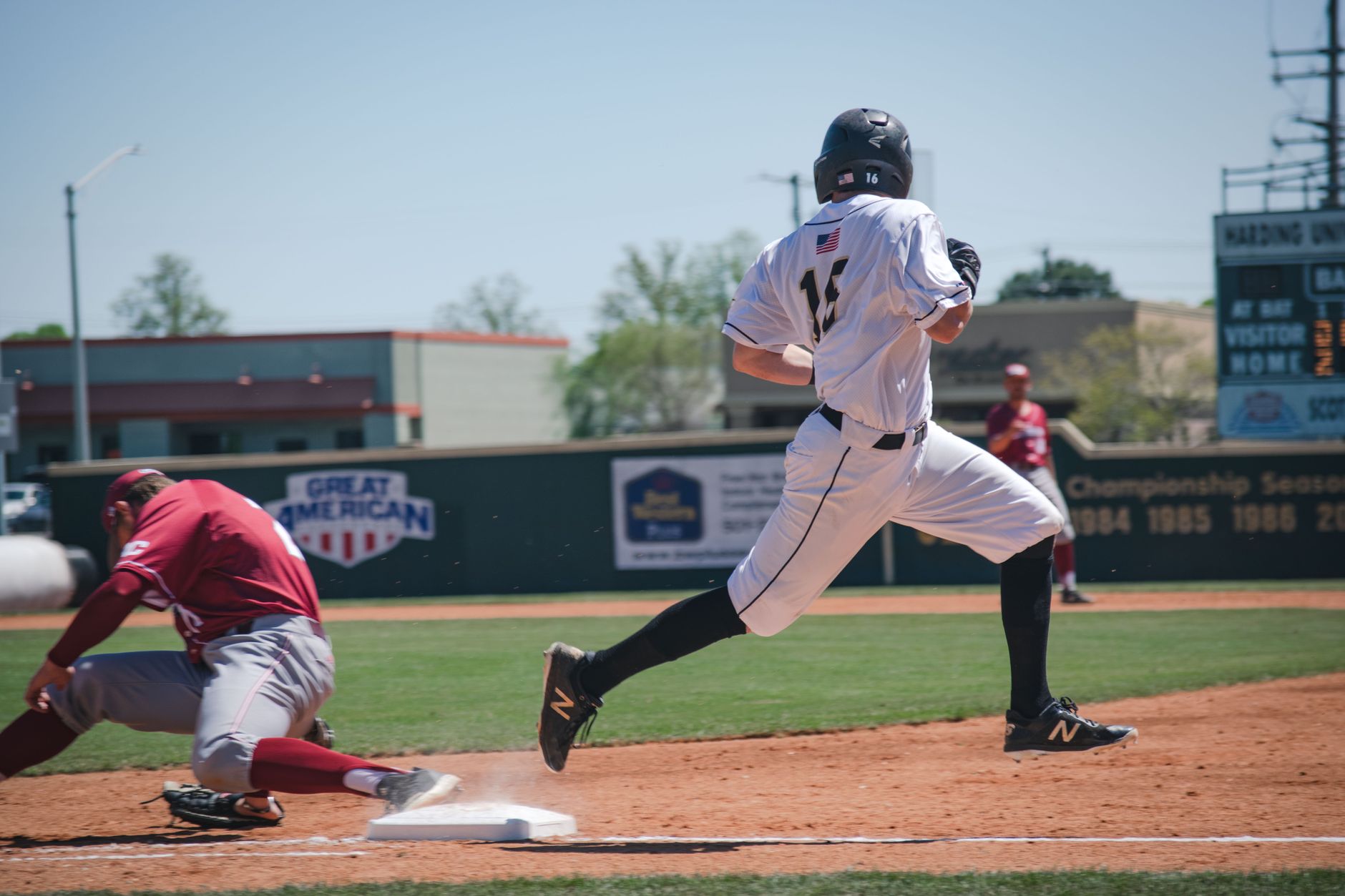 Two baseball players compete in an intense game at Harding University Stadium, showcasing sportsmanship and action.
