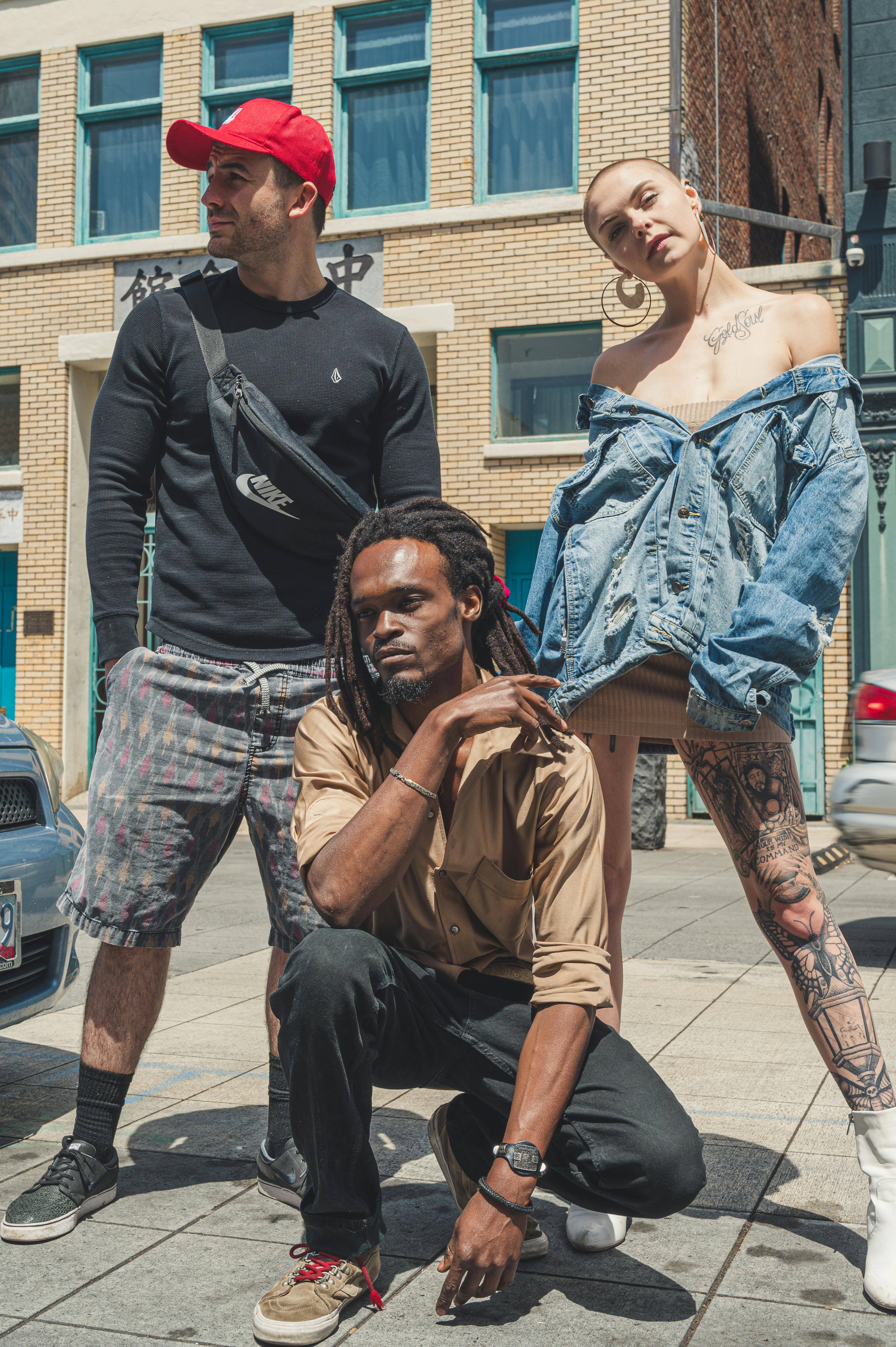 Group of diverse young adults posing stylishly on an urban street in daylight.