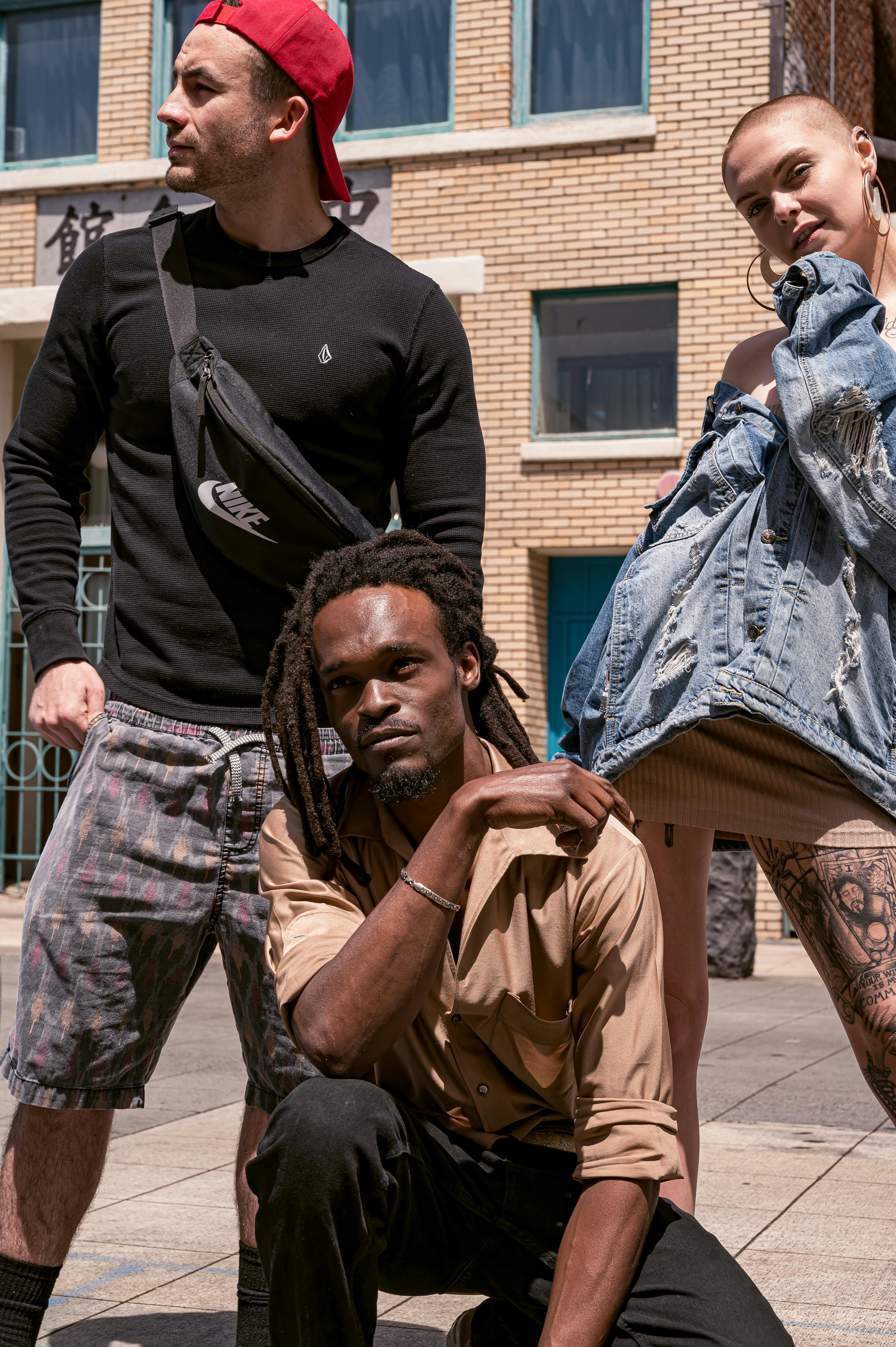 A stylish group poses confidently in an urban outdoor street setting.