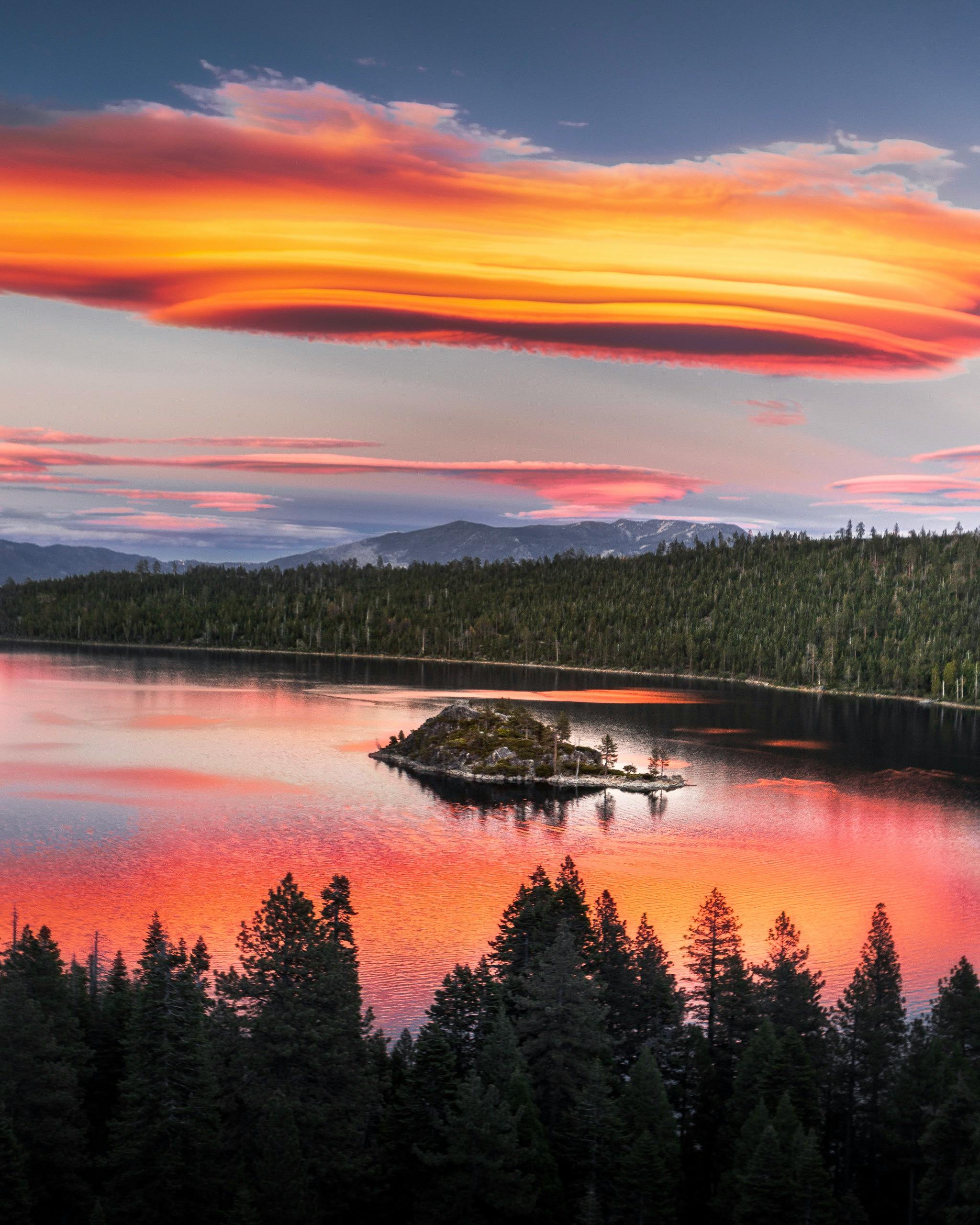 令人惊叹的日落倒映在宁静的山区湖泊中，天空色彩生动，四周郁郁葱葱