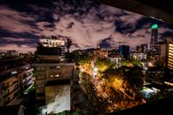 圣地亚哥的天际线在夜间呈现出戏剧性的景观，建筑物灯火通明，天空多云