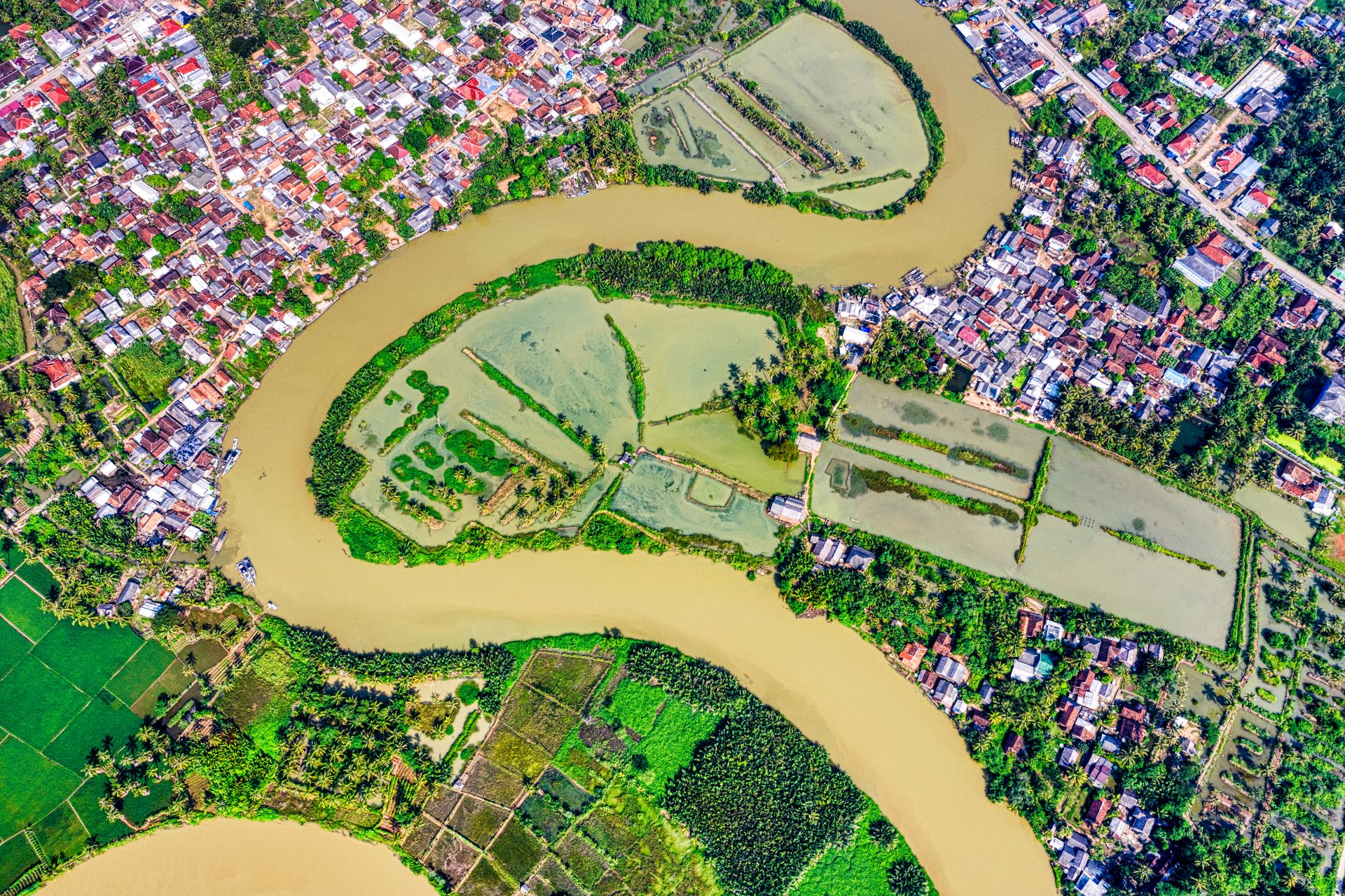 Vibrant aerial view of a river bending through lush farmland and a rural town.