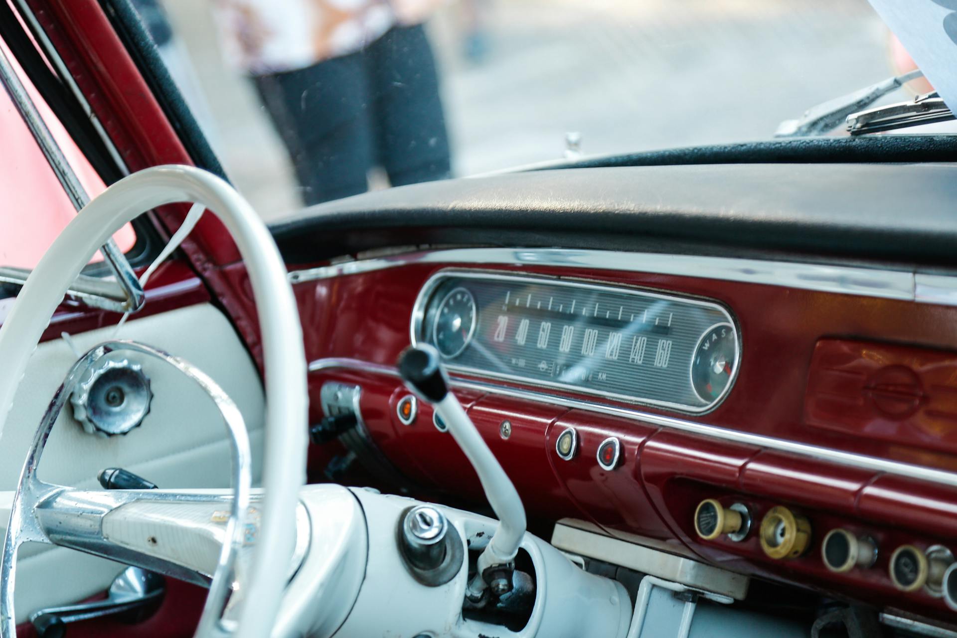 Detailed view of a vintage red car interior featuring a classic dashboard and steering wheel.