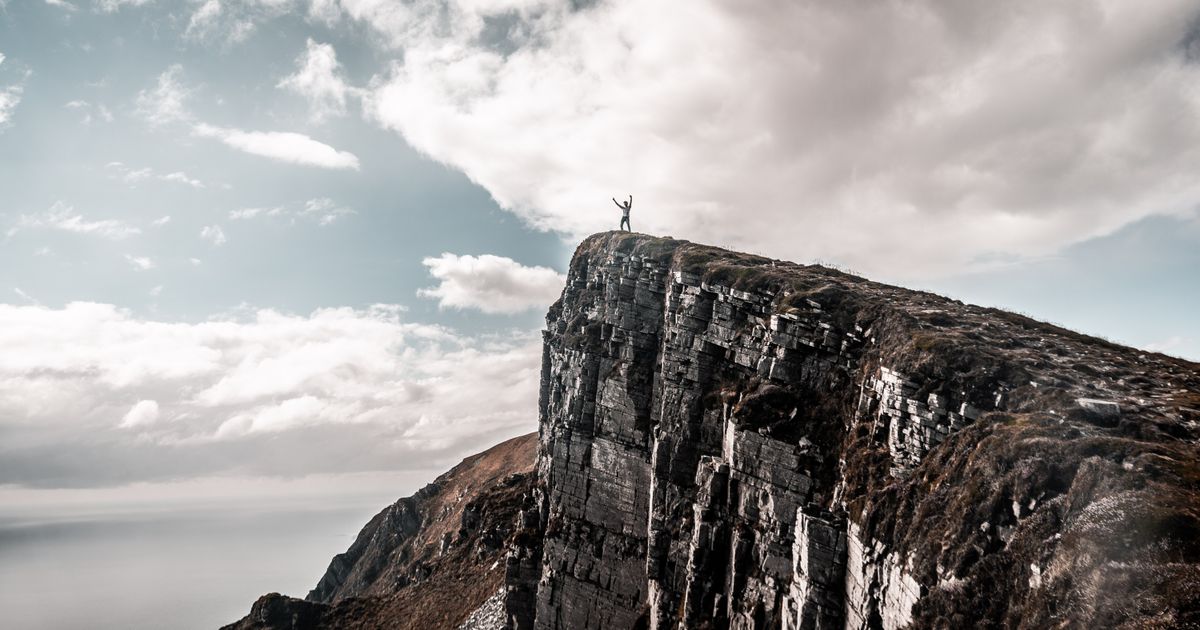 A person standing on a cliff edge overlooking a drop, representing a market top during Wyckoff distribution