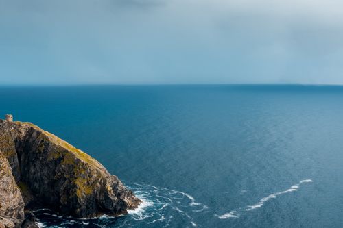 Free A stunning view of rocky cliffs jutting into the vast ocean under a clear blue sky. Stock Photo