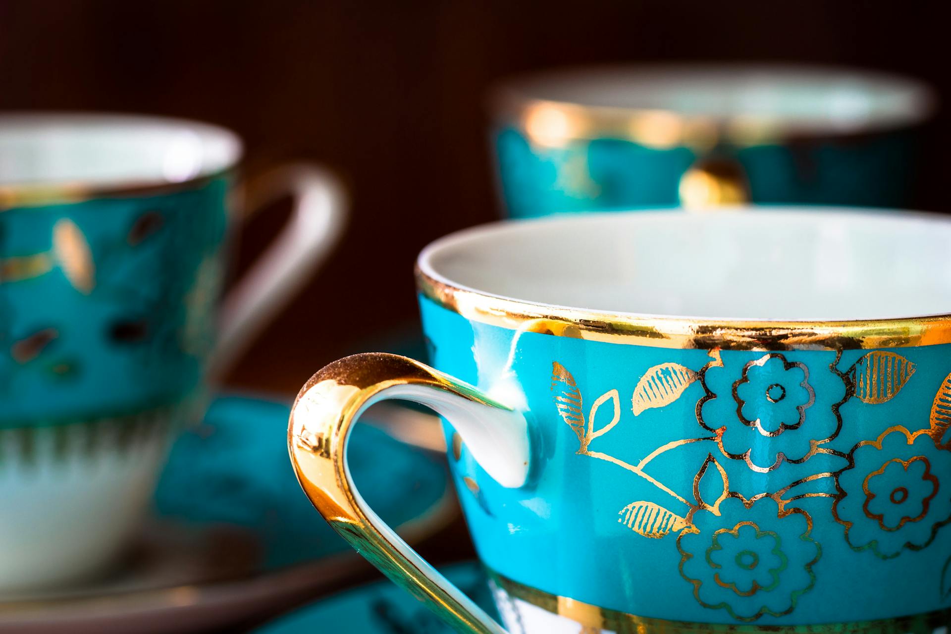 Close-up of elegant blue porcelain teacups adorned with gold floral patterns.