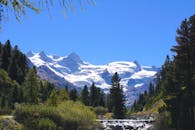白雪皑皑的山脉景色令人惊叹，湛蓝的天空下，前景中一条河流静静流淌