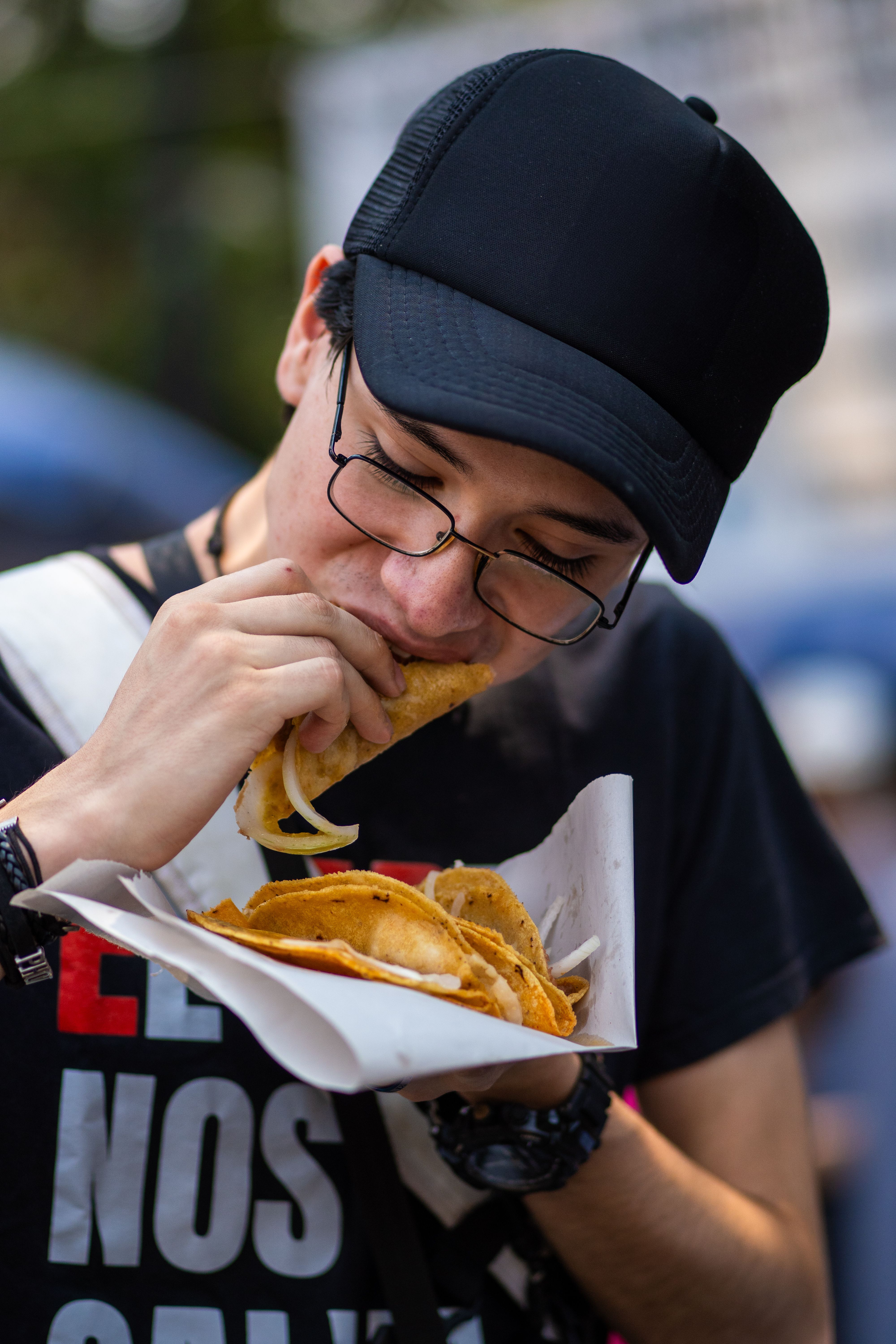 A man eating a taco while wearing a hat · Free Stock Photo