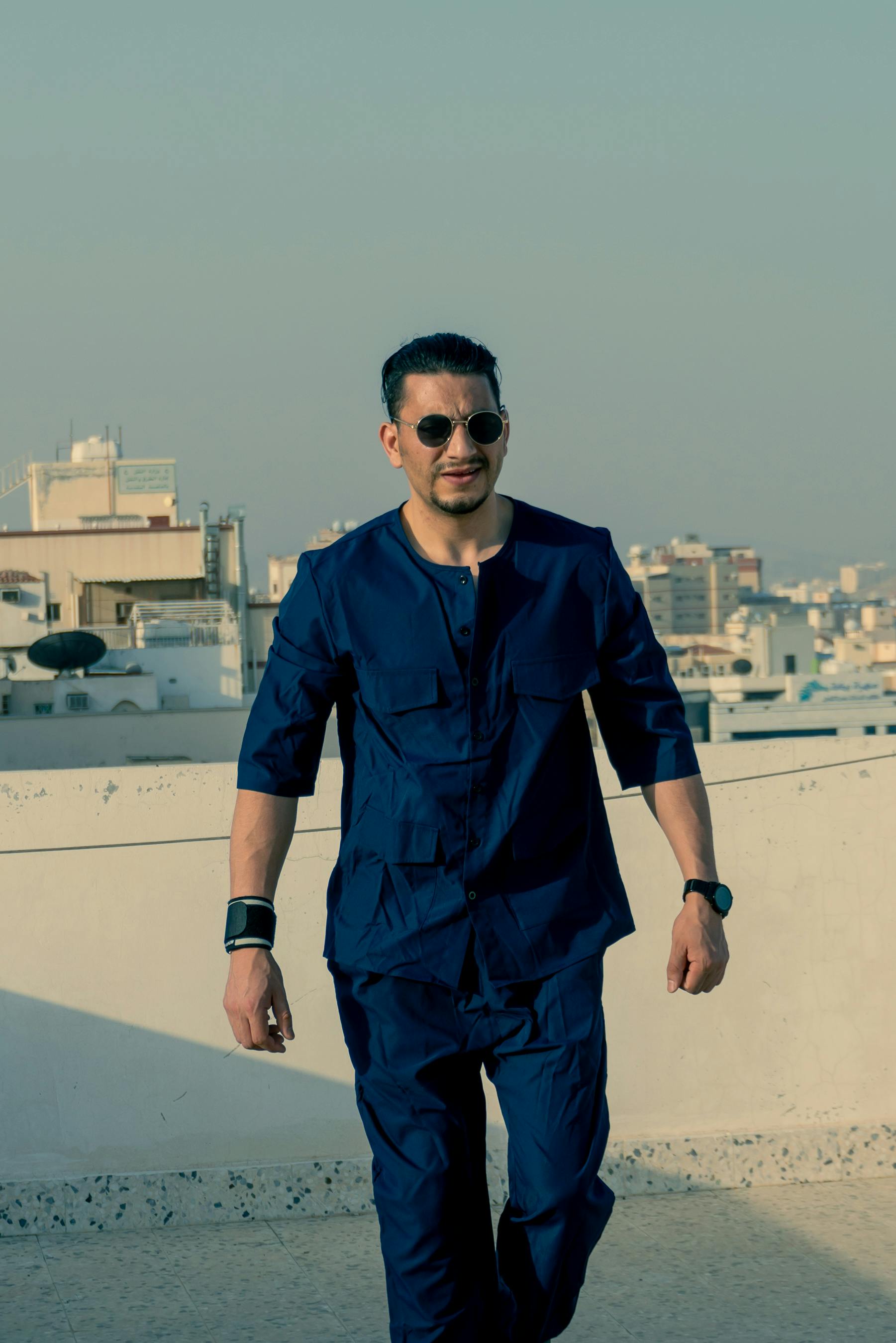 Fashionable man posing outdoors on a city rooftop, exuding urban style and confidence.
