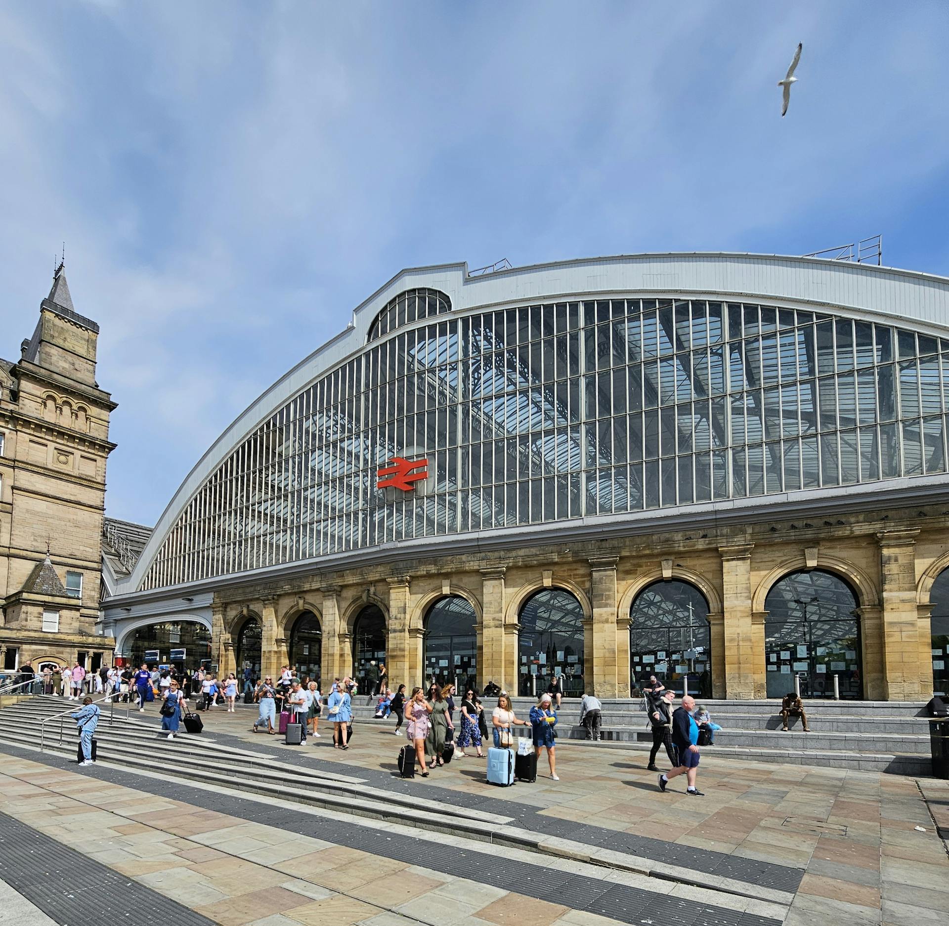 A bustling scene outside Liverpool Lime Street Station with travelers and iconic architecture.