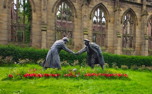 Free Statues of soldiers shaking hands amidst flowering garden in Liverpool, UK. Stock Photo