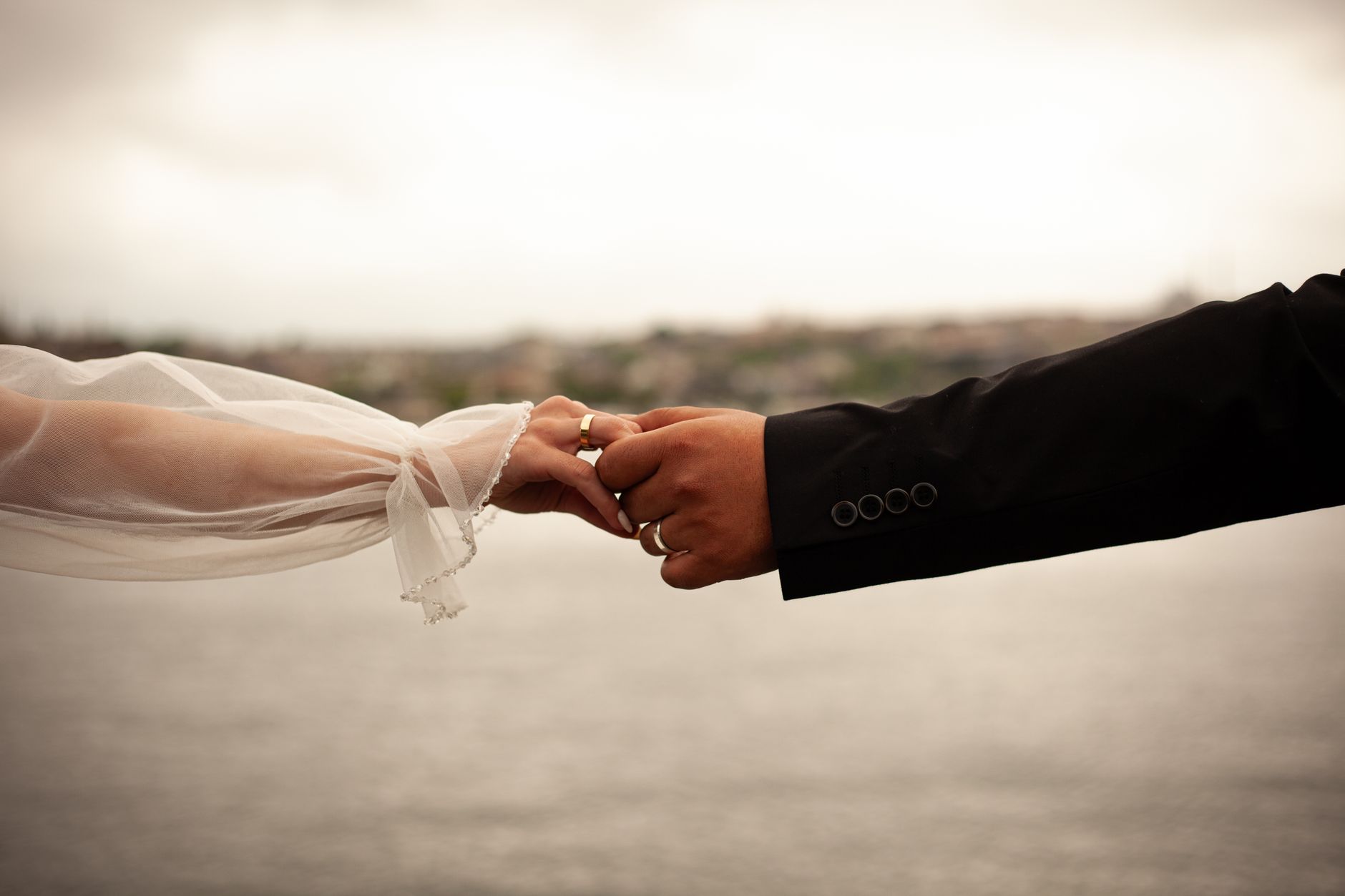 Close-up of a couple holding hands in wedding attire, symbolizing love and unity.