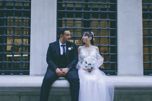 Free Bride and groom sitting together, sharing a romantic moment outdoors. Stock Photo