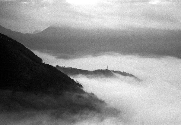 Grainy monochrome hillside above a sea of fog — photo by Q. Hưng Phạm on Pexels
