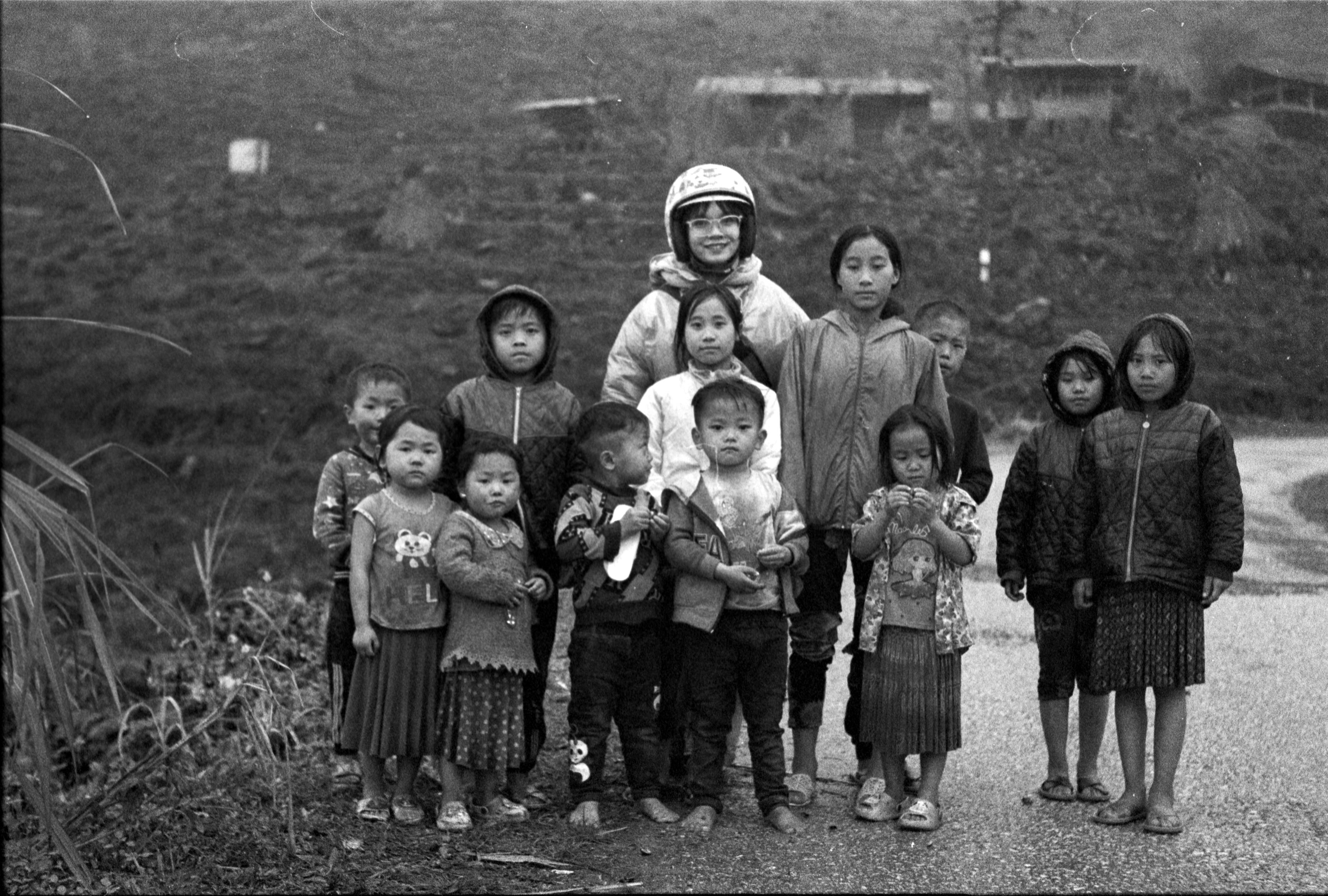 Group of children posing on a rural path in a black and white photo, conveying exploration and community.