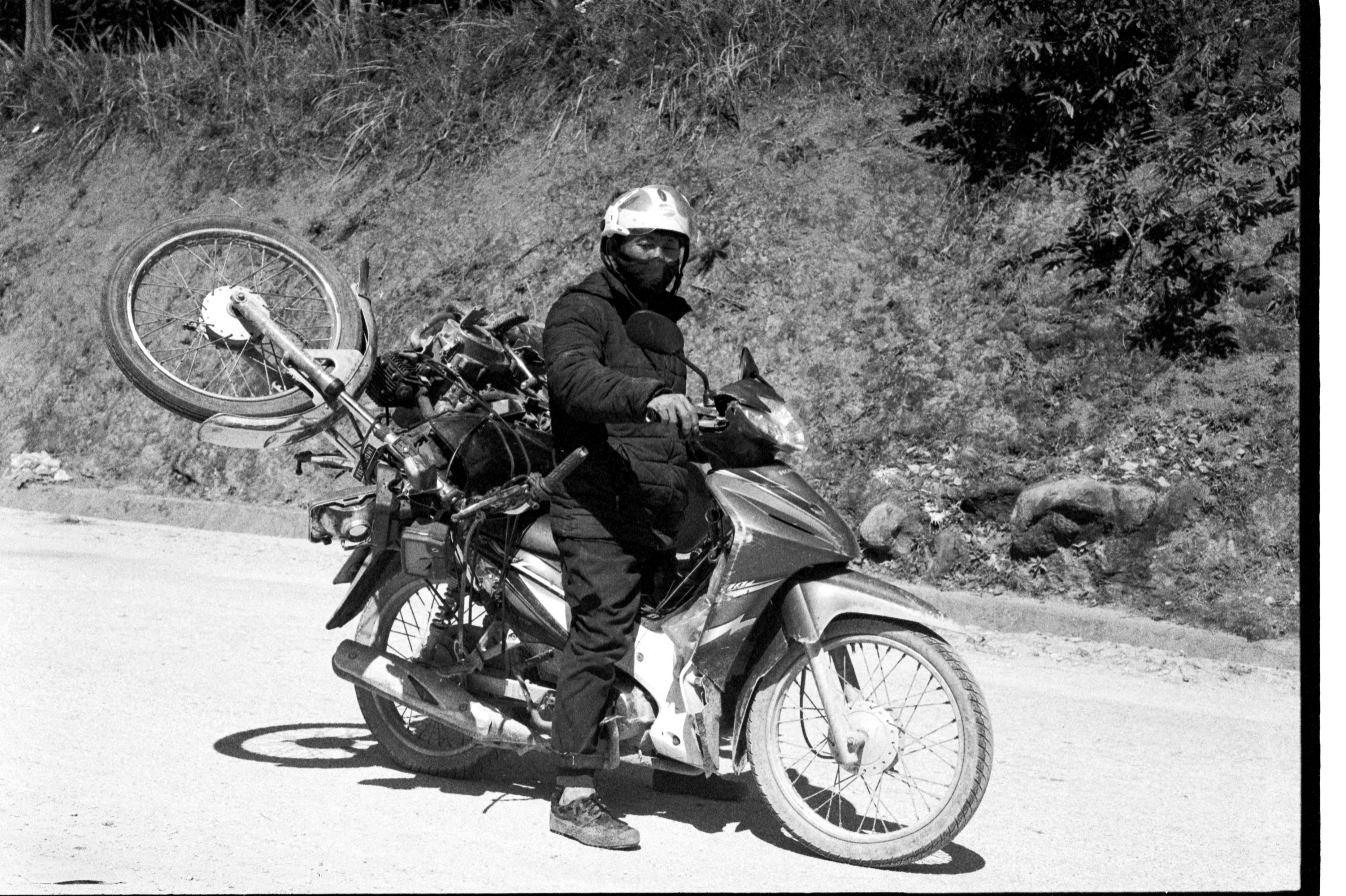 Man on motorbike with extra wheels, showcasing street culture and transportation.