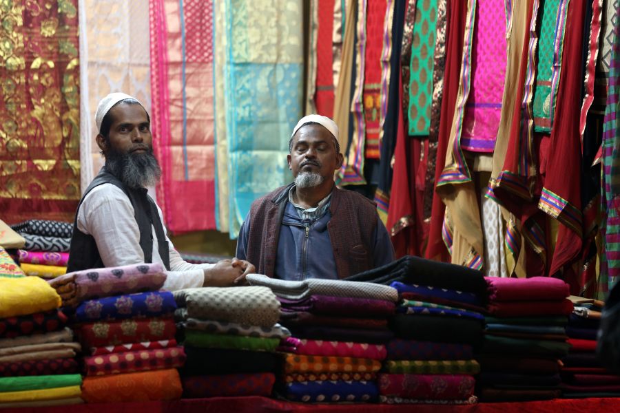 Two men inside a colourful Indian textile shop