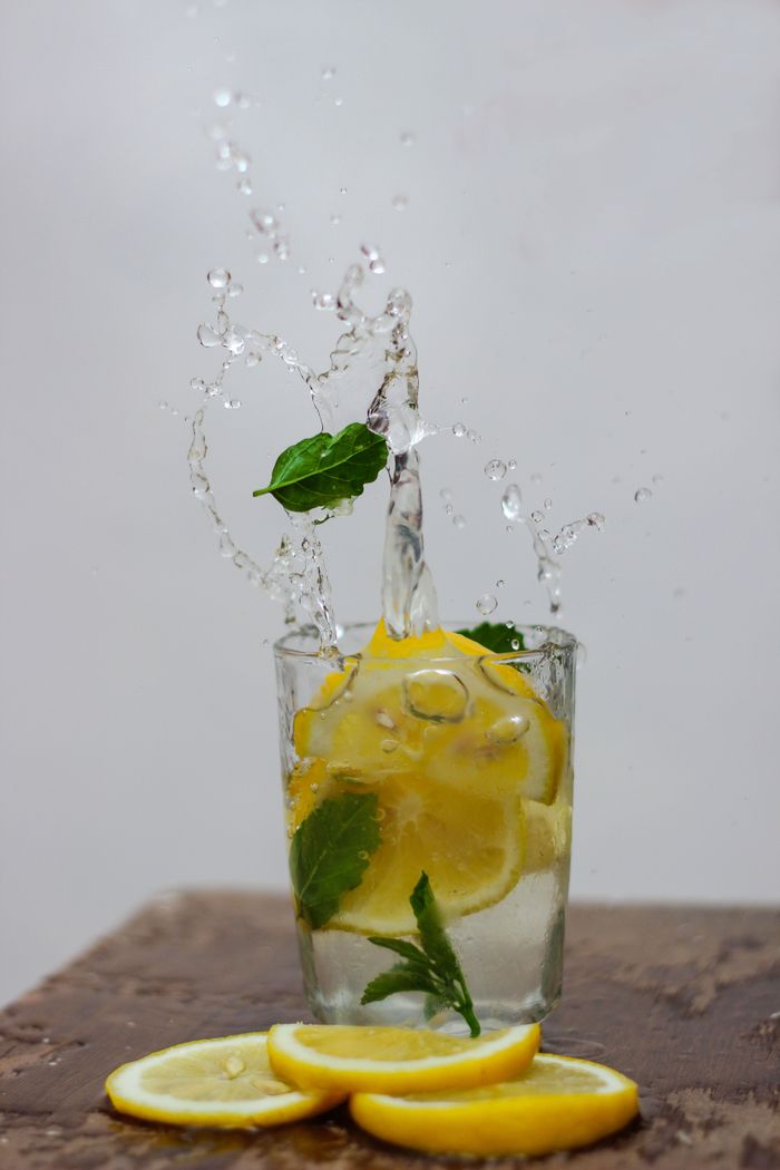 Lemon and mint slices splashing in water in a refreshing still life