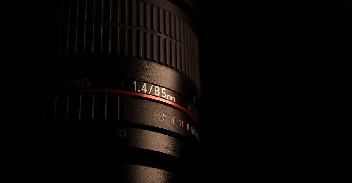 Detailed close-up of an 85mm camera lens showcasing aperture settings with a dark, moody tone.