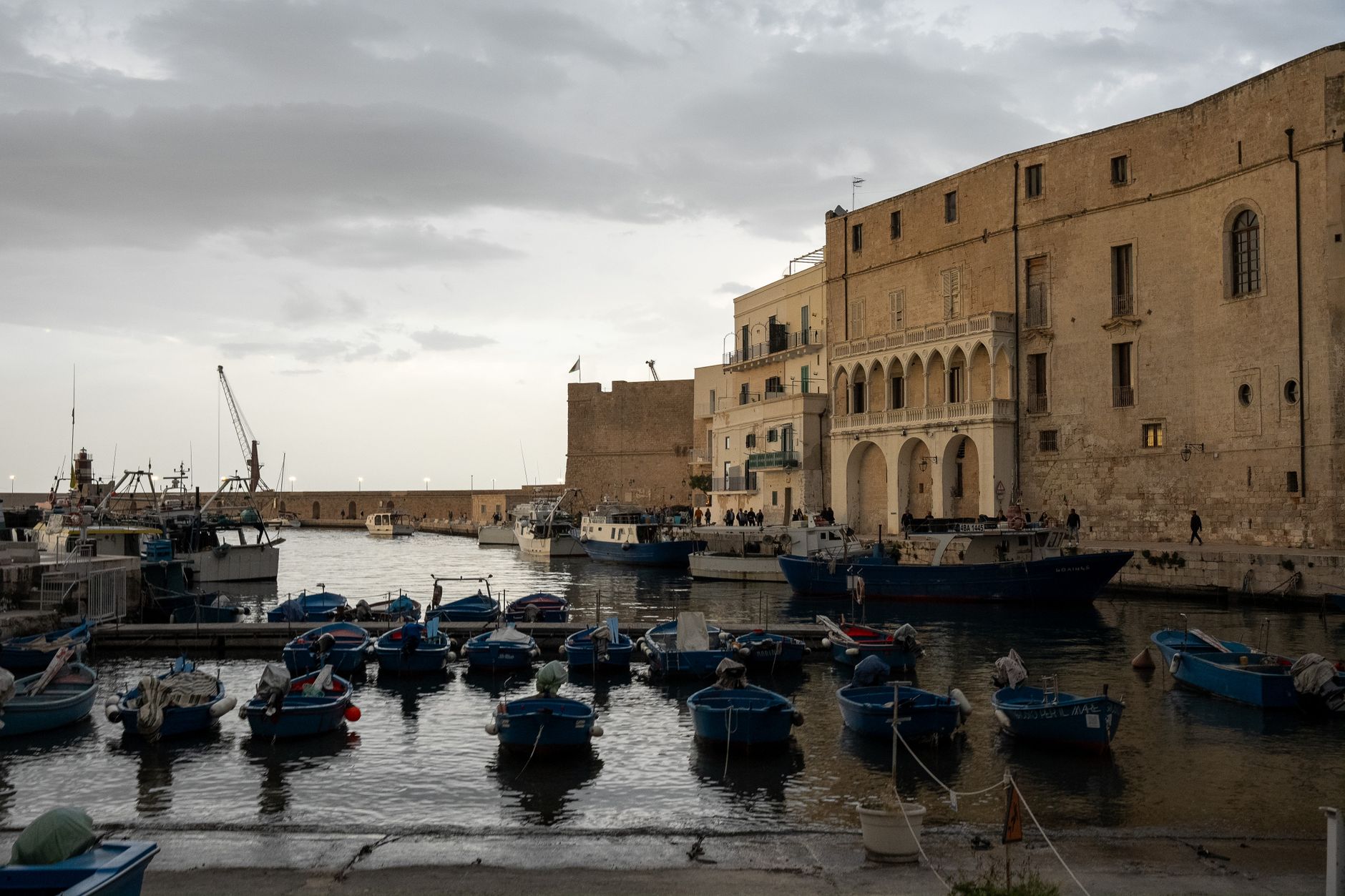 Veduta serale del porto storico di Monopoli con barche e architettura pugliese.