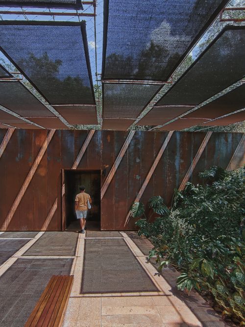Free A man walks into a modern building surrounded by lush plants in Brumadinho, Brazil. Stock Photo
