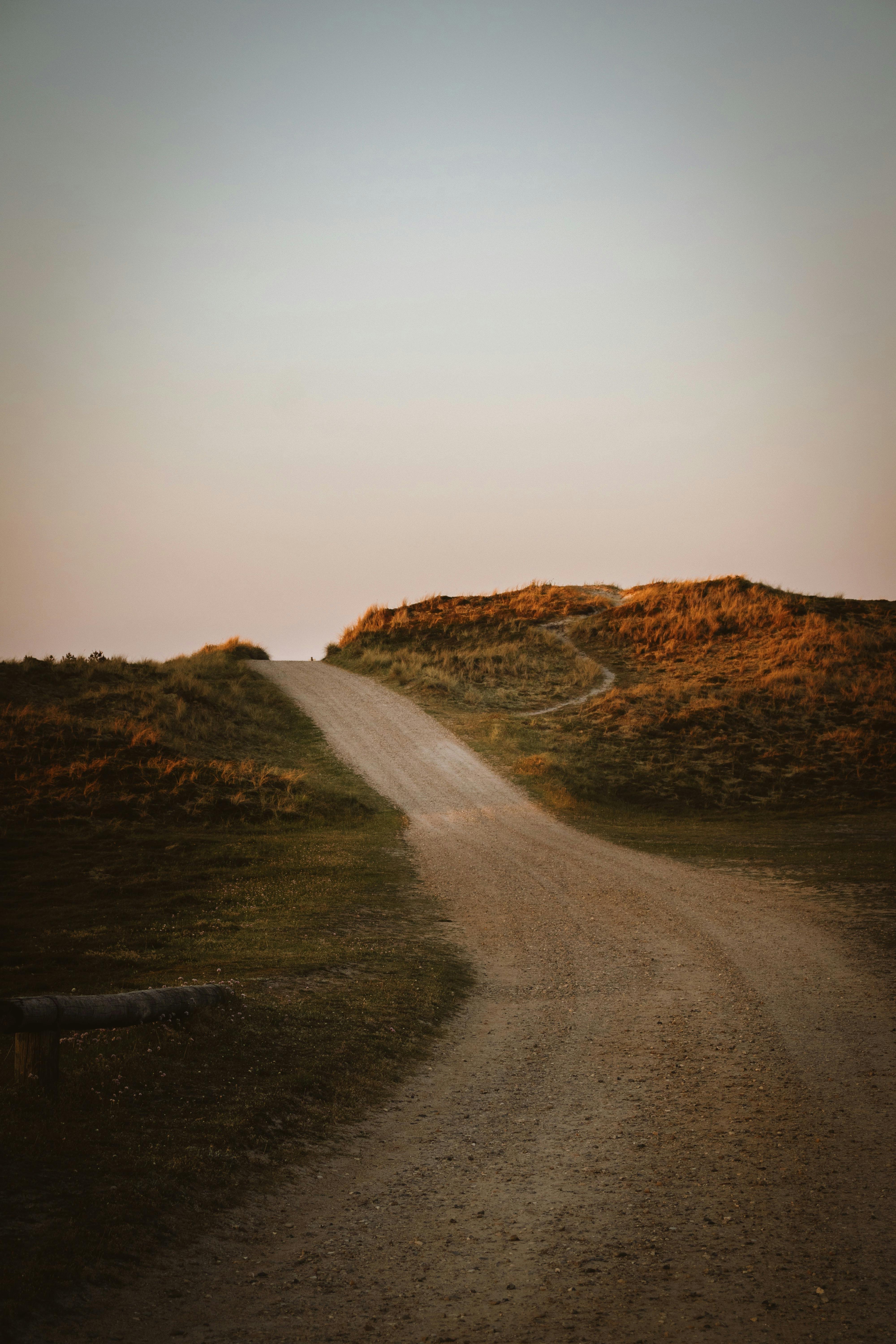 Serene dirt path winding through the dunes of Denmark at sunset, showcasing natural beauty and tranquility.