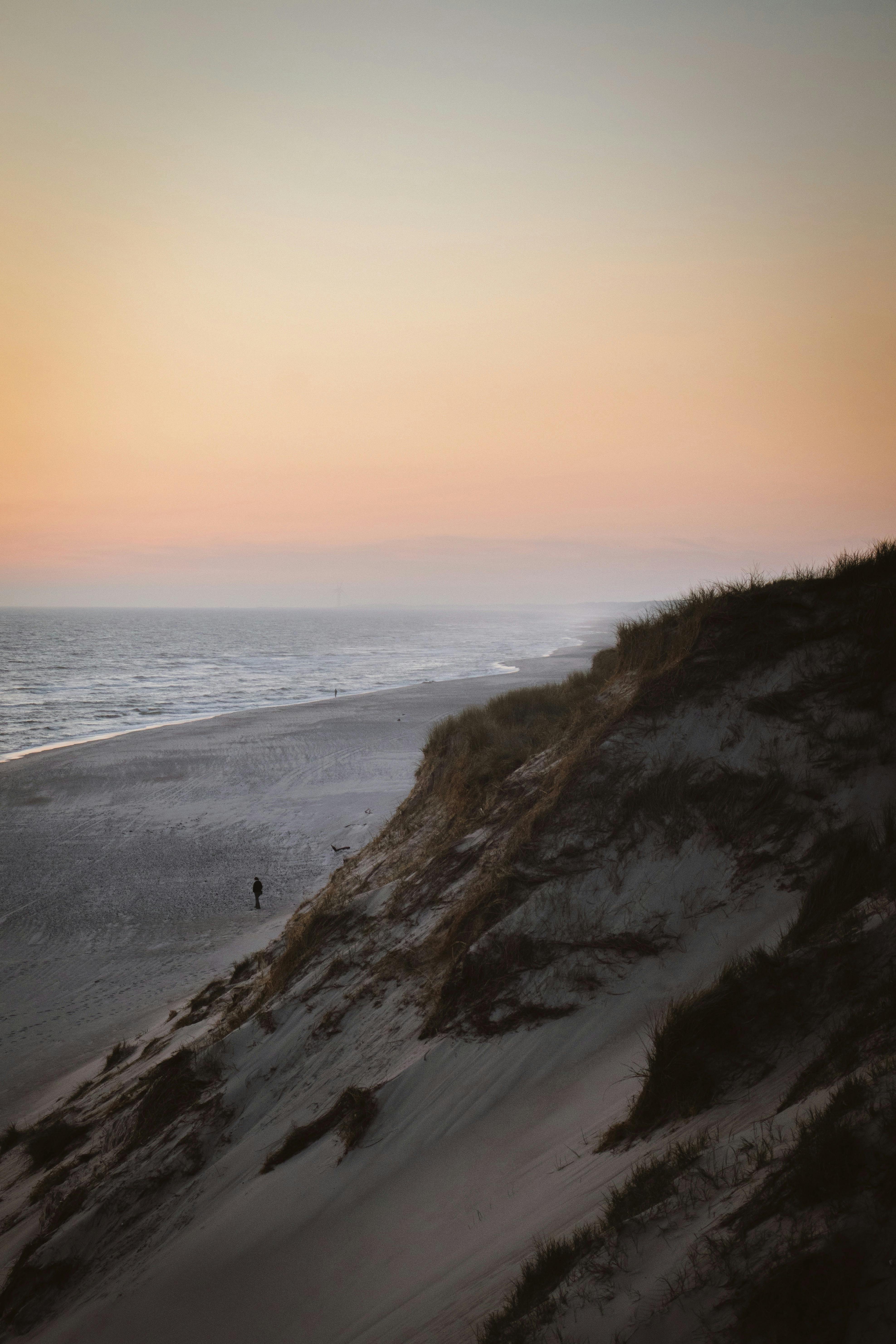 Peaceful view of Denmark's sandy dunes and ocean at sunset, creating a tranquil coastal scene.