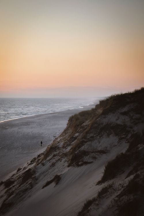 Free Peaceful view of Denmark's sandy dunes and ocean at sunset, creating a tranquil coastal scene. Stock Photo