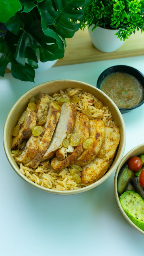 Free Appetizing bowl of grilled chicken with rice and a side of mixed vegetables, perfect for a healthy meal. Stock Photo